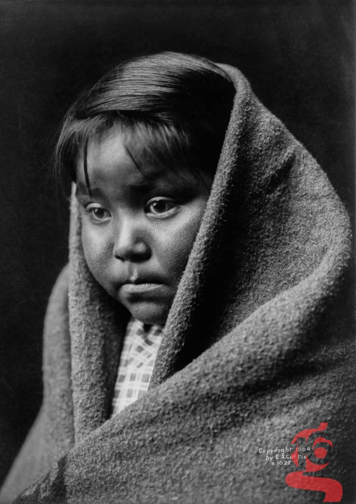 Portrait d’une enfant diné enveloppée dans une couverture, photographiée par Edward S. Curtis vers 1904.