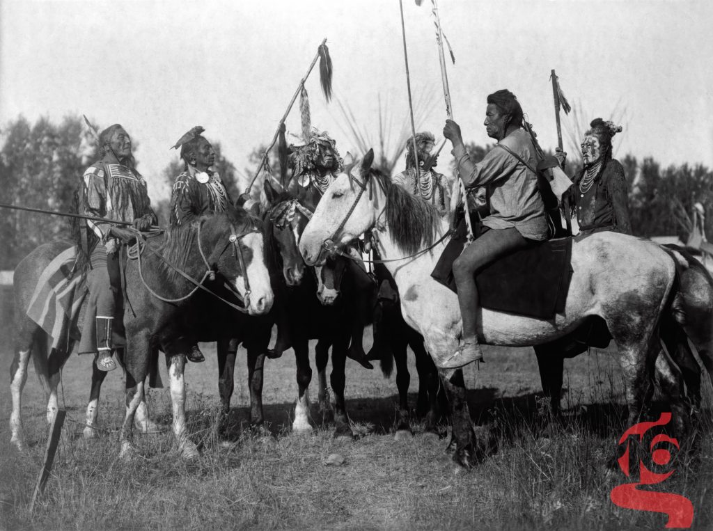 Groupe de chefs blackfeet réunis à cheval avec des lances cérémonielles, photographiés par Edward S. Curtis vers 1900.