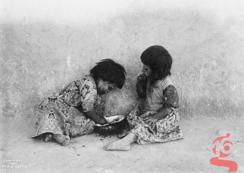 Deux jeunes filles hopies assises au sol et mangeant des melons, photographiées par Edward S. Curtis vers 1900.