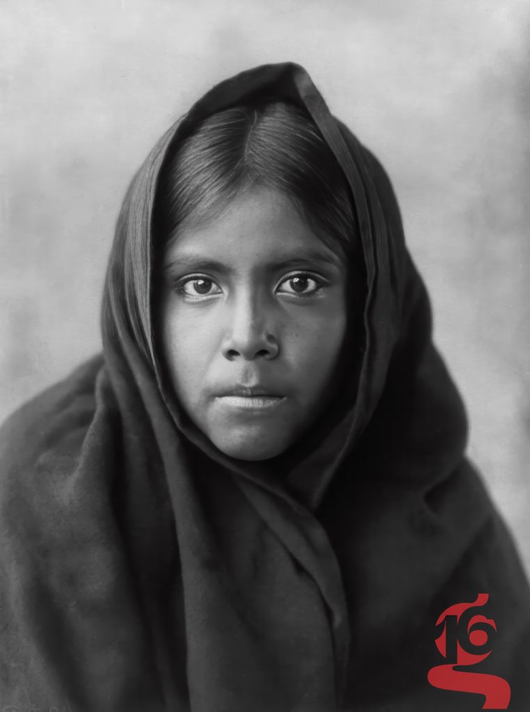 Portrait frontal d’une jeune fille tohono o’odham enveloppée dans un châle, photographiée par Edward S. Curtis en 1907.