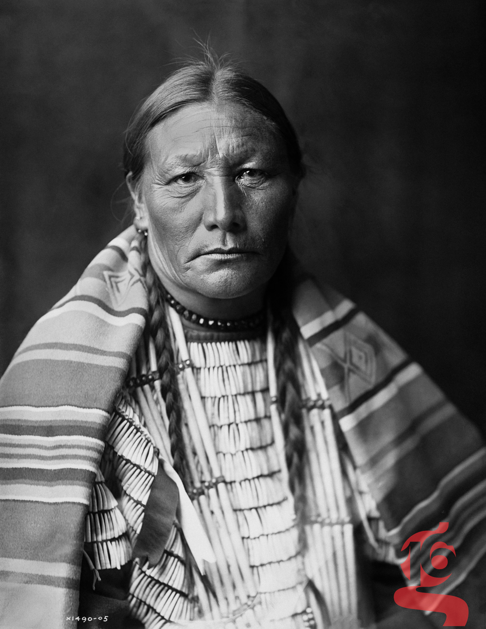 Portrait d’une femme sioux portant une couverture rayée et une parure de coquillages, photographiée par Edward S. Curtis en 1905.