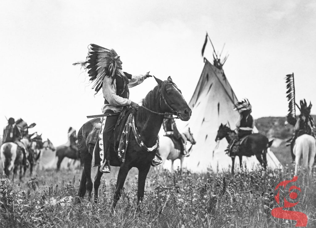Plusieurs hommes lakotas à cheval autour d’un tipi dans Start of a War Party, photographie d’Edward S. Curtis de 1907.