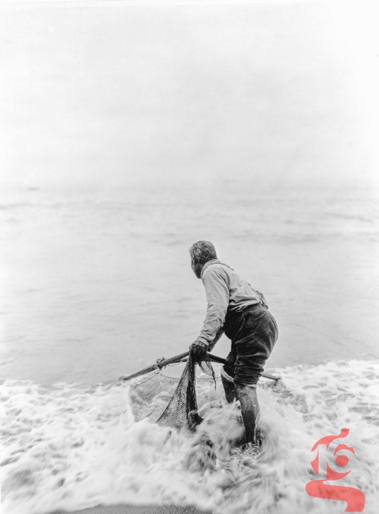 Pêcheur yurok utilisant un filet de plage dans les vagues à Trinidad, photographié par Edward S. Curtis en 1923.