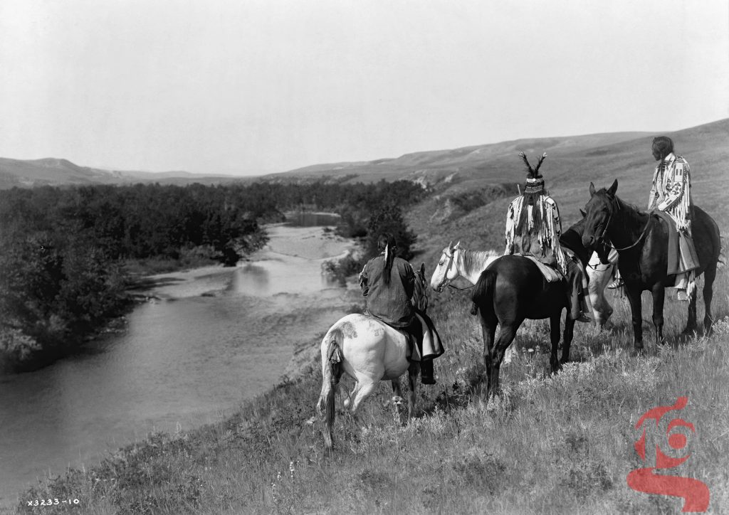 Trois cavaliers Piegan et quatre chevaux sur une colline dominant une rivière, Edward S. Curtis, 1910