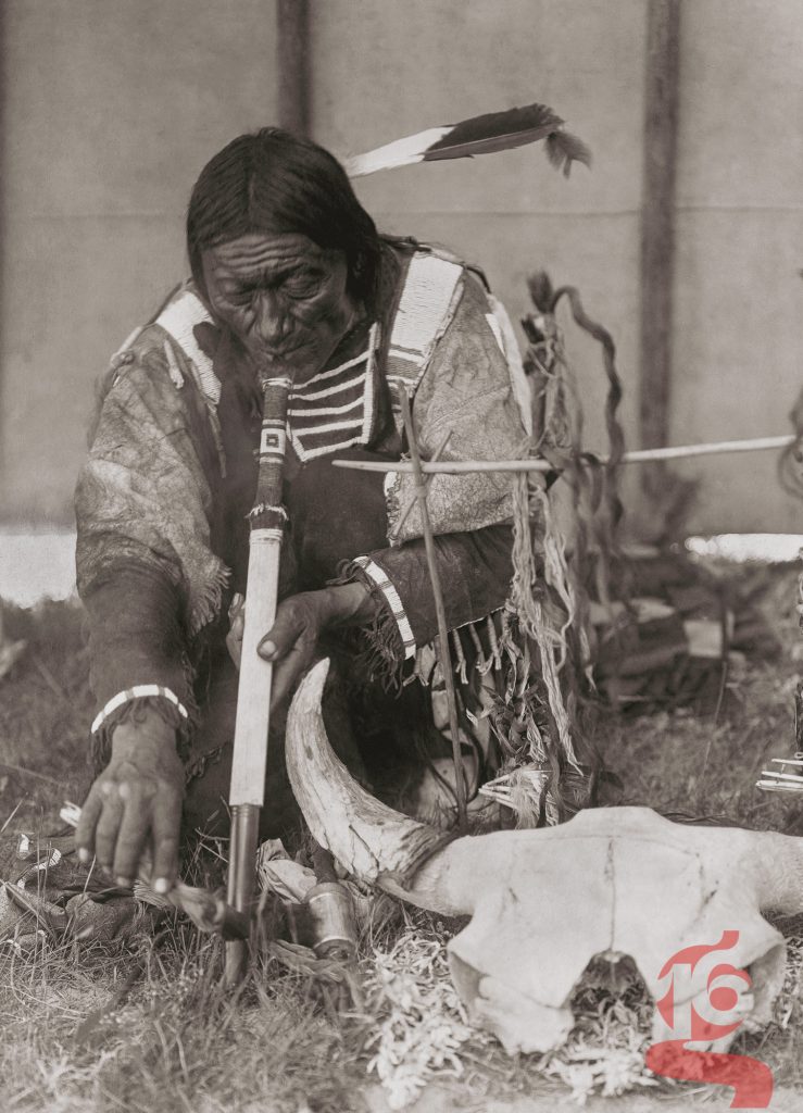 Broad Tail, homme piegan agenouillé avec une pipe cérémonielle, photographié par Edward S. Curtis en 1910.