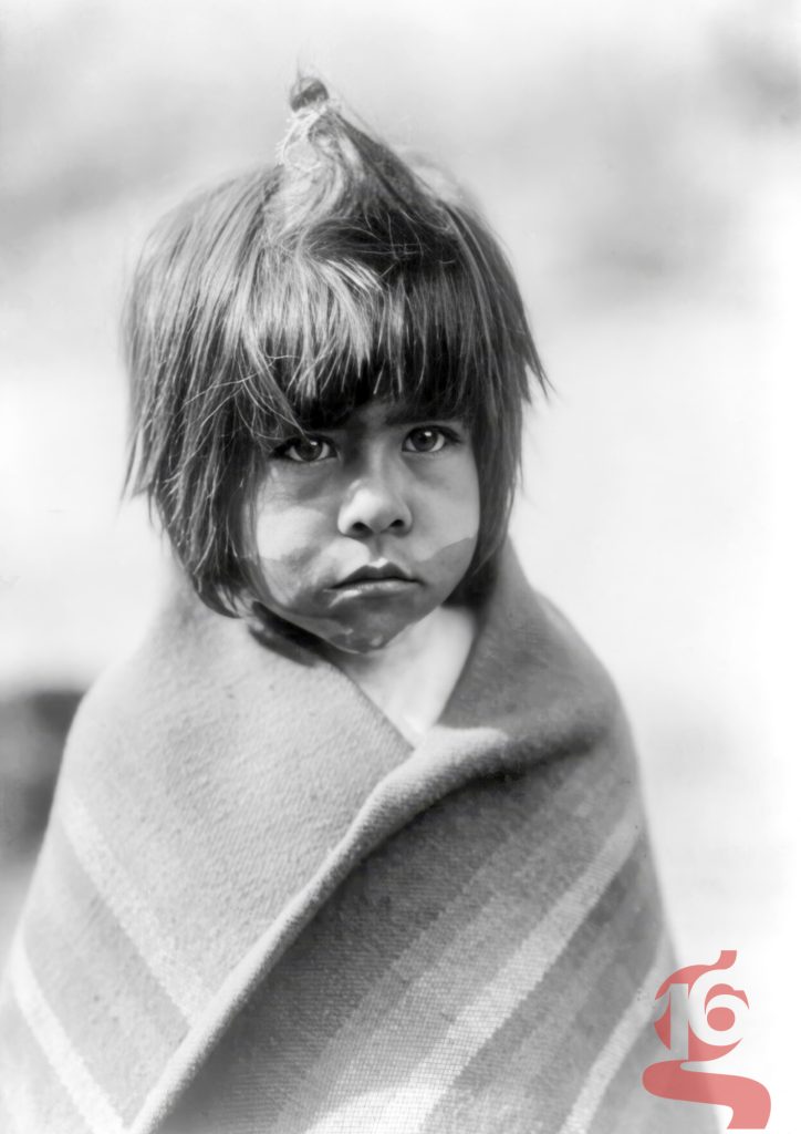 Portrait d’un jeune garçon Chemehuevi enveloppé dans une couverture, photographié en Arizona par Edward S. Curtis vers 1907.