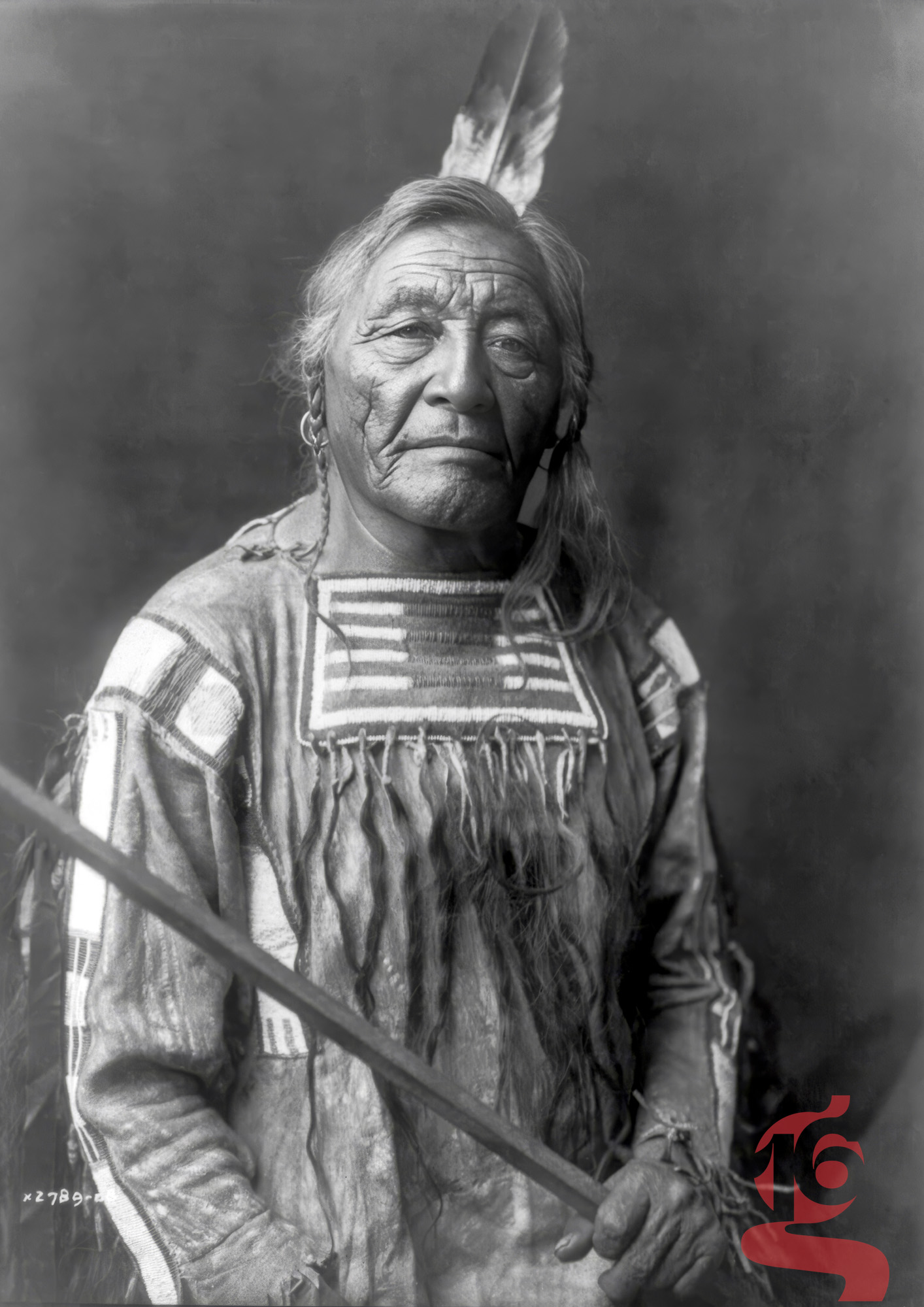 Portrait de Sitting Elk, homme apsáalooke Crow tenant un bâton et portant une plume, photographié par Edward S. Curtis en 1908.