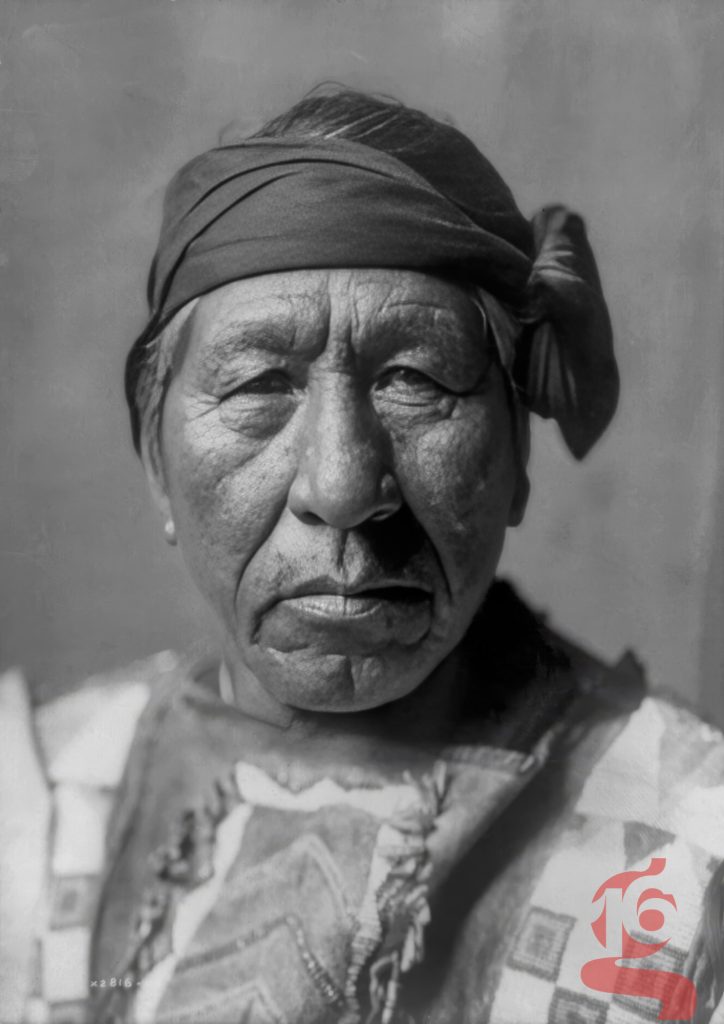 Portrait rapproché de Sitting Owl, homme hidatsa portant un bandeau noué autour de la tête, photographié par Edward S. Curtis vers 1908.