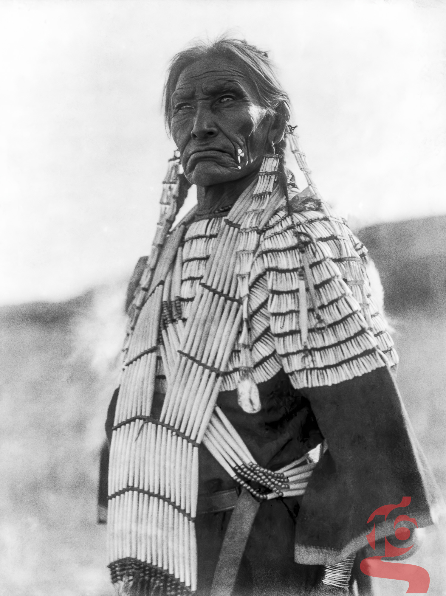Portrait de Slow Bull, homme oglala lakota portant un vêtement richement orné, photographié par Edward S. Curtis en 1907.