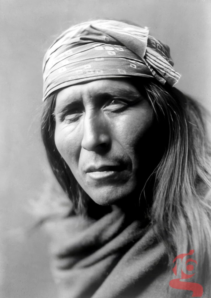 Portrait rapproché de Tsahizn Tseh, homme apache aux cheveux longs portant un bandeau, photographié par Edward S. Curtis en 1906.